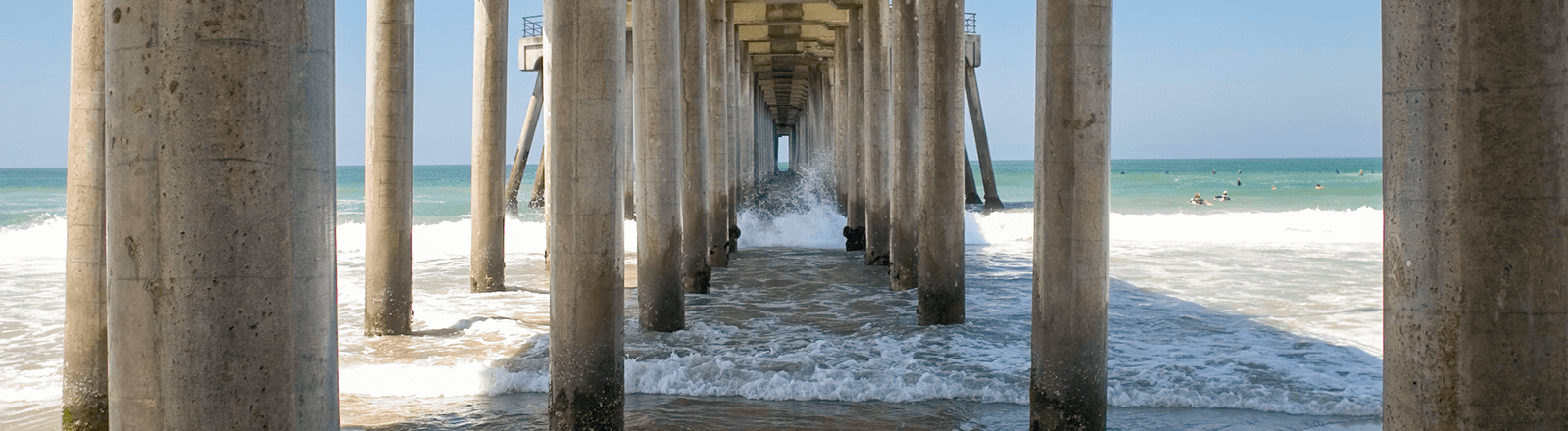 pylons and water underneath the huntington beach pier
